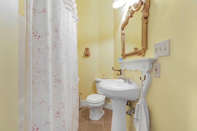 bathroom featuring tile patterned floors, toilet, sink, and curtained shower