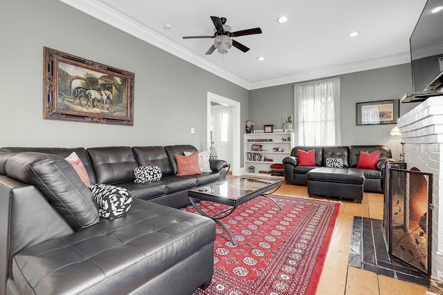 living room featuring ceiling fan, a brick fireplace, crown molding, and light hardwood / wood-style floors