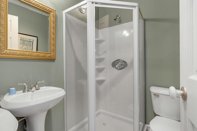 bathroom featuring a shower with shower door and toilet