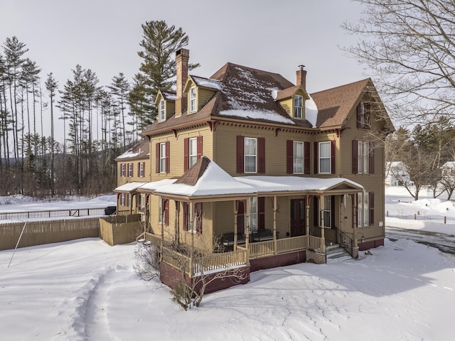 snow covered rear of property with covered porch