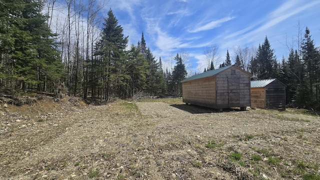 77 Currie Rd, Oakfield, ME 04780 - view of yard with a storage unit, an outbuilding, and a view of trees