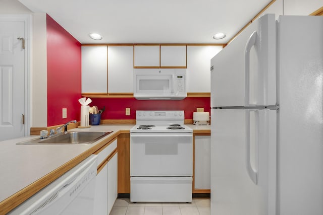 kitchen with white appliances, sink, light tile floors, and white cabinetry