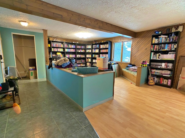 office area with beamed ceiling, wooden walls, a textured ceiling, and hardwood / wood-style flooring