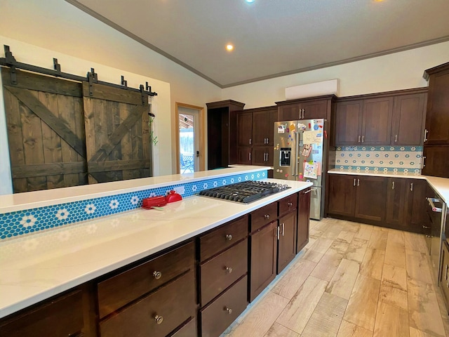kitchen featuring a barn door, stainless steel appliances, and backsplash