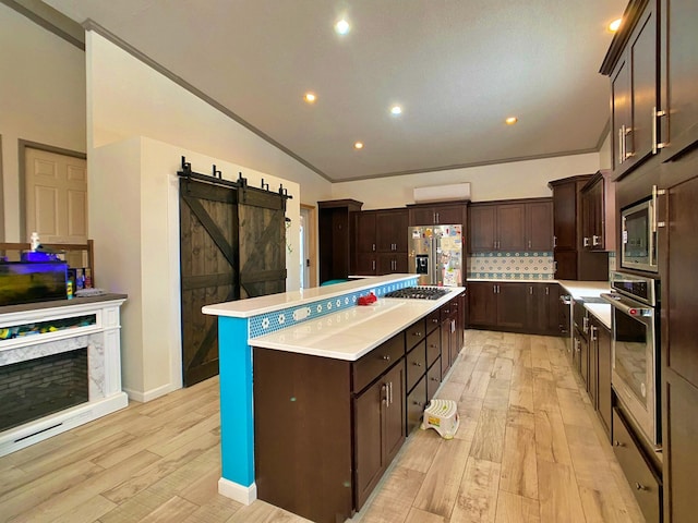 kitchen featuring tasteful backsplash, stainless steel appliances, vaulted ceiling, a barn door, and a kitchen island
