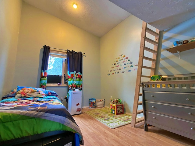 bedroom featuring a textured ceiling, lofted ceiling, and wood-type flooring