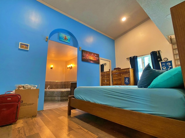 bedroom with high vaulted ceiling, wood-type flooring, and ornamental molding