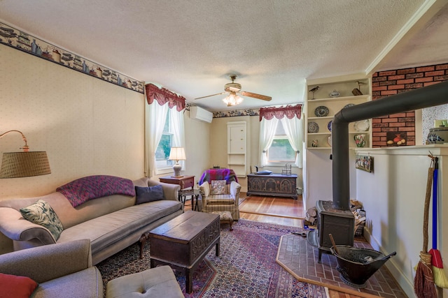 living room with a textured ceiling, hardwood / wood-style floors, a wood stove, and a wealth of natural light