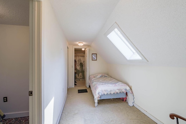 unfurnished bedroom featuring light carpet, a textured ceiling, baseboards, visible vents, and lofted ceiling with skylight