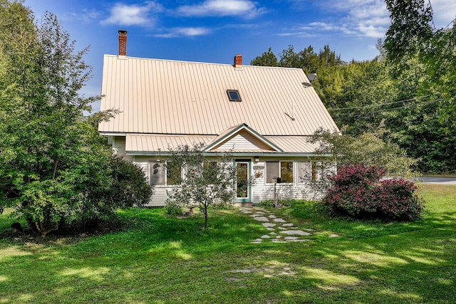 view of front of property with a front lawn, a chimney, and metal roof