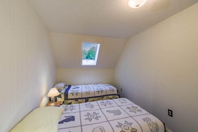 bedroom with a textured ceiling and lofted ceiling with skylight