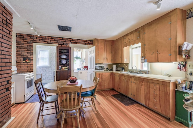 kitchen with light hardwood / wood-style floors, white range with gas stovetop, a textured ceiling, track lighting, and sink