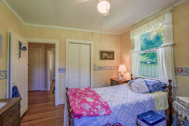 bedroom with a closet, a textured ceiling, wood-type flooring, ceiling fan, and ornamental molding