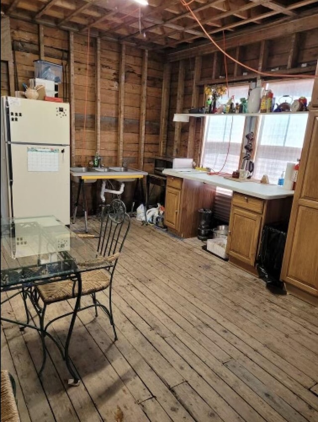 kitchen featuring light hardwood / wood-style floors, wood walls, and white fridge