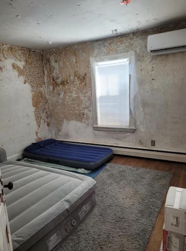 unfurnished bedroom featuring dark hardwood / wood-style flooring, baseboard heating, and a wall unit AC