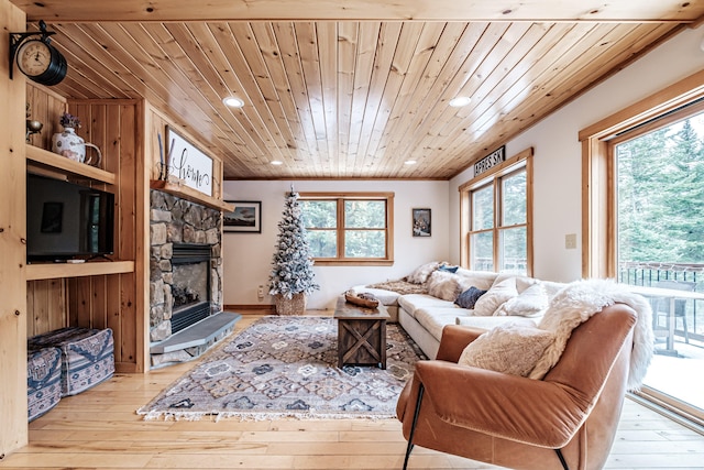 living room featuring a wealth of natural light, wood ceiling, a stone fireplace, and hardwood / wood-style flooring