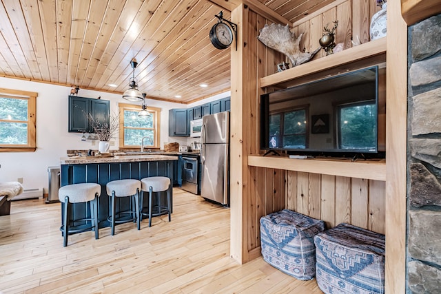 kitchen featuring stainless steel appliances, light wood-style flooring, blue cabinets, wooden ceiling, and a kitchen bar