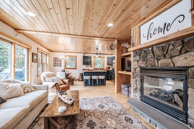 living area featuring a notable chandelier, a stone fireplace, wooden ceiling, and light wood-style floors