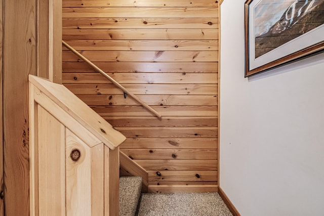 staircase featuring carpet floors and wood walls