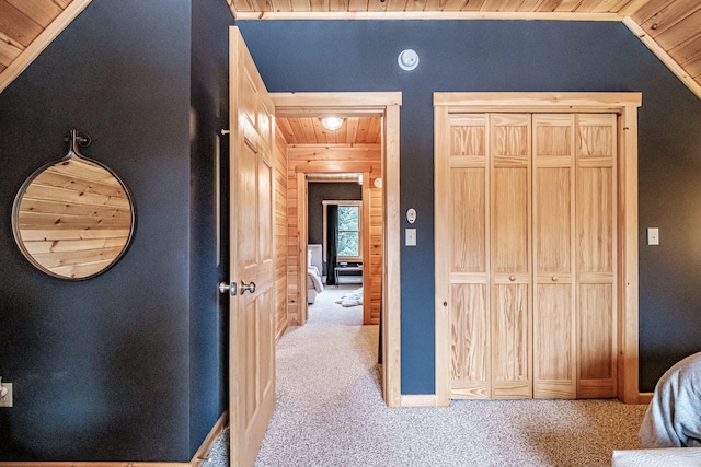 hall with carpet floors, lofted ceiling, and wood ceiling