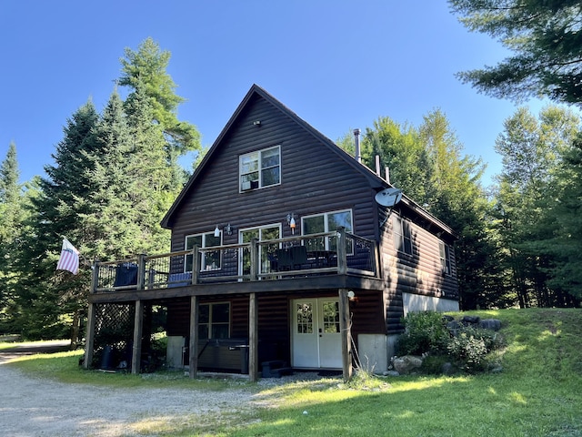 rear view of house featuring faux log siding, a lawn, and a deck