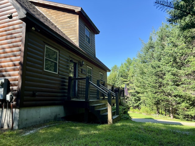 view of property exterior with a shingled roof and a yard