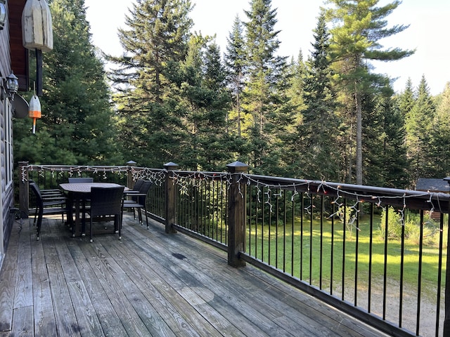 wooden deck with a yard and outdoor dining space