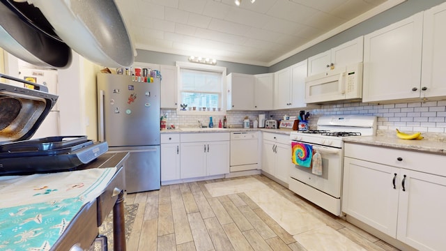 kitchen featuring white cabinetry, backsplash, white appliances, light hardwood / wood-style floors, and sink