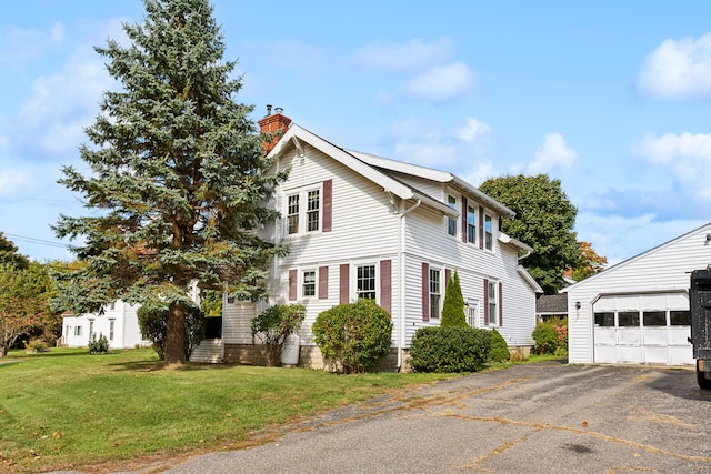 view of property exterior with a yard, an outdoor structure, and a garage