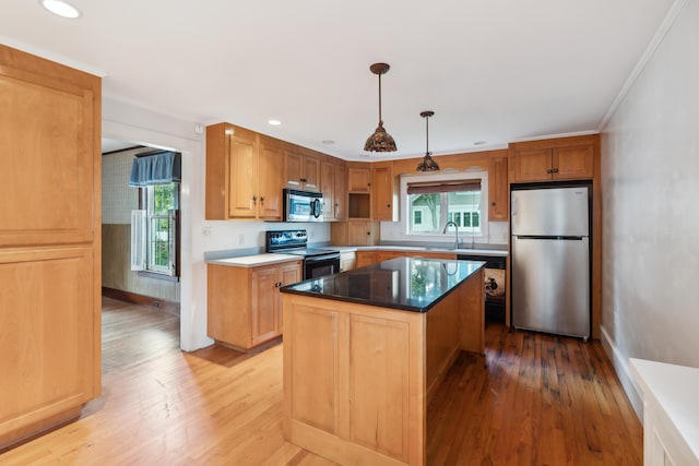 kitchen with appliances with stainless steel finishes, light wood-type flooring, hanging light fixtures, and a center island