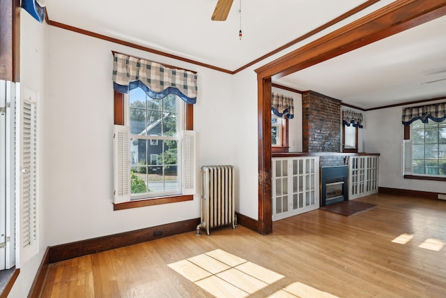 interior space with hardwood / wood-style flooring, crown molding, ceiling fan, and radiator