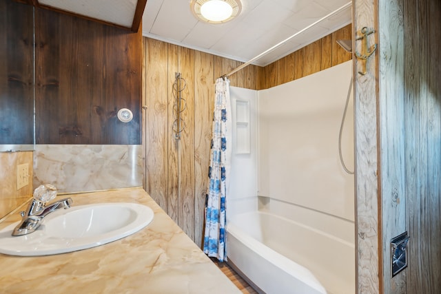 bathroom with shower / bath combination with curtain, vanity, and wooden walls