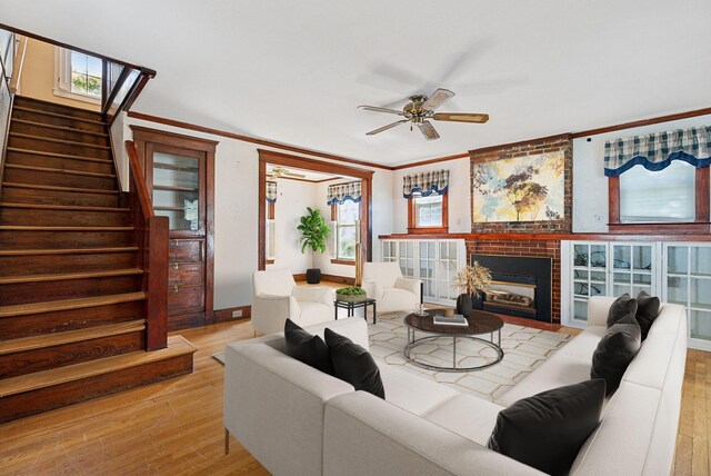 living room with ceiling fan, a fireplace, crown molding, and light hardwood / wood-style floors