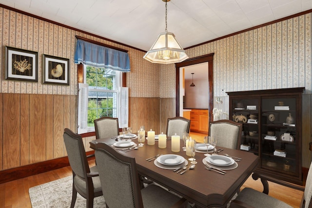 dining area with wooden walls, light hardwood / wood-style flooring, and ornamental molding