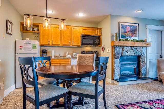 kitchen with a fireplace, sink, white appliances, light carpet, and pendant lighting