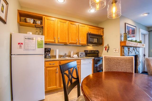 kitchen with sink, black appliances, a stone fireplace, and decorative light fixtures