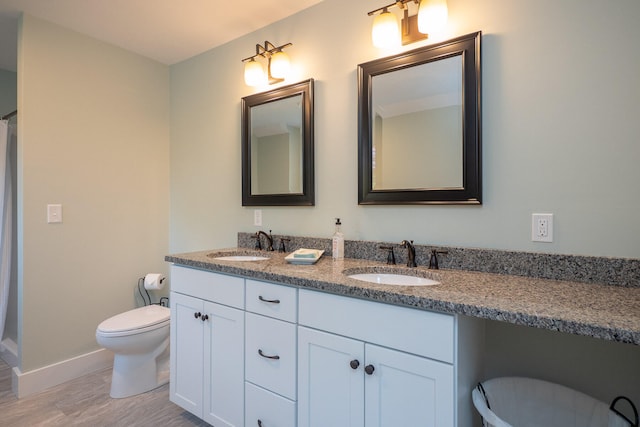 bathroom featuring hardwood / wood-style flooring, double sink vanity, and toilet