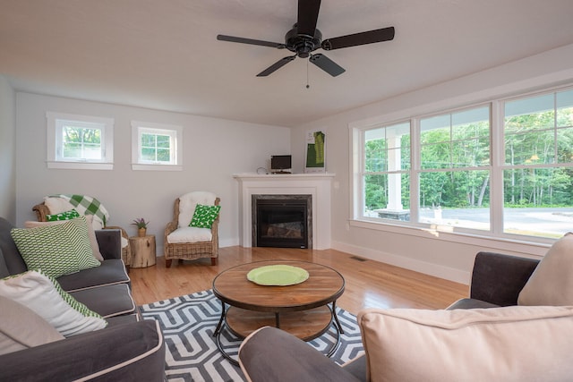 living room with ceiling fan, light wood-type flooring, and a wealth of natural light