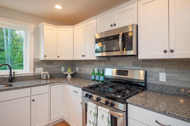 kitchen with backsplash, stainless steel appliances, white cabinetry, and sink