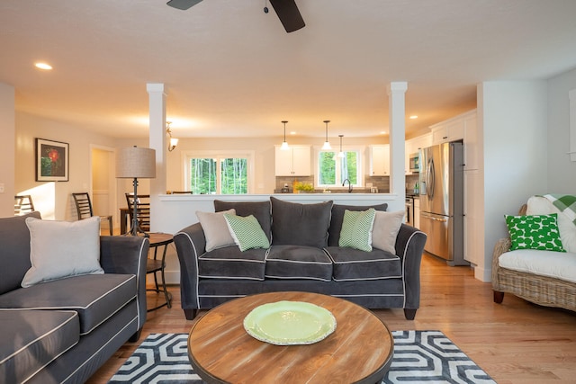 living room featuring sink, ceiling fan, decorative columns, and light hardwood / wood-style flooring