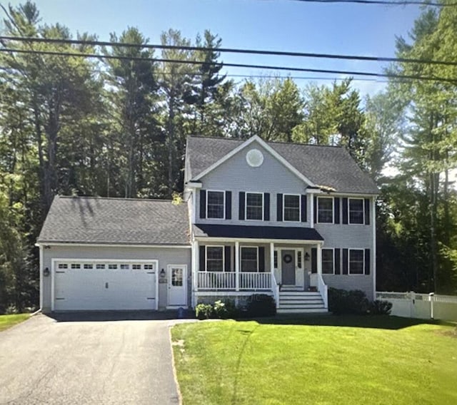 colonial home with a porch, a front lawn, and a garage