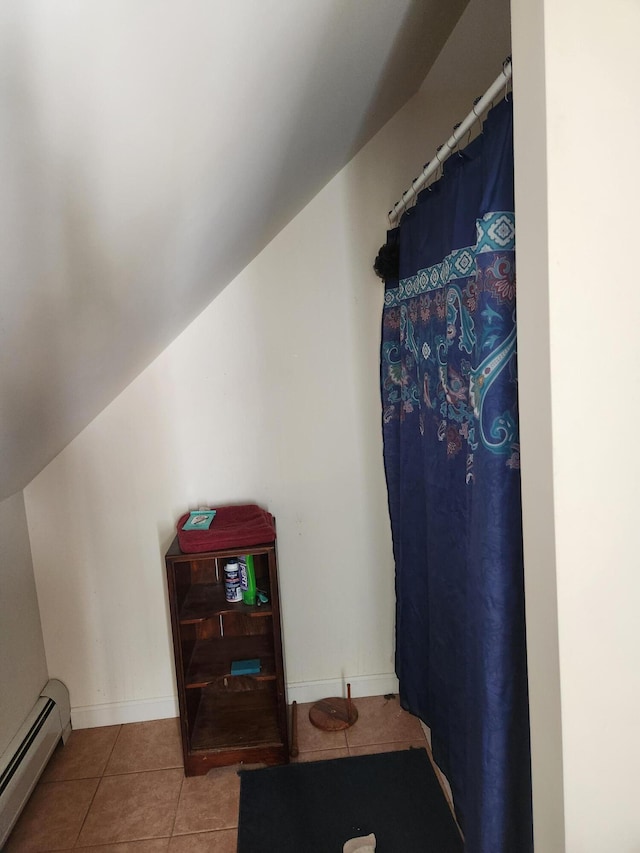 interior space with tile patterned floors, a baseboard heating unit, and vaulted ceiling