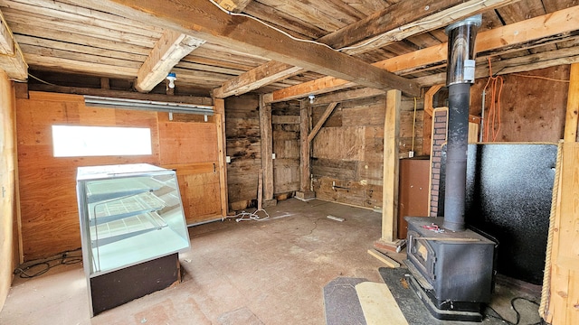 basement featuring wooden walls and a wood stove