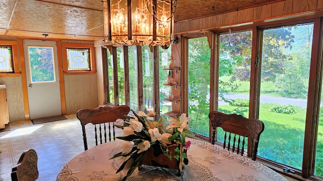 unfurnished dining area with a notable chandelier, wooden walls, and wooden ceiling