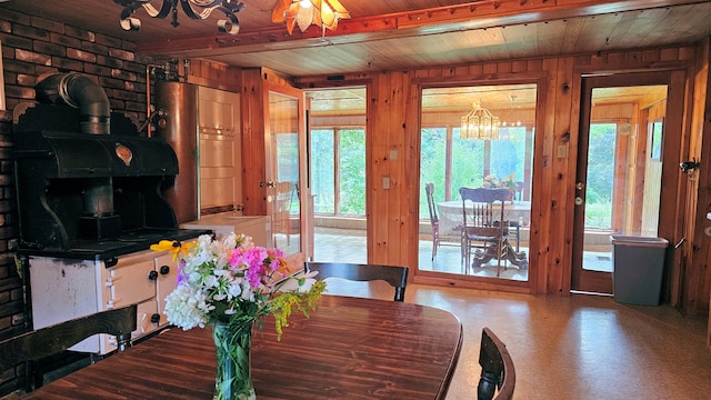 dining area with wood ceiling, beamed ceiling, wooden walls, and a wood stove