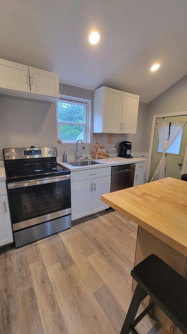 kitchen featuring sink, light wood-type flooring, white cabinets, stainless steel range with electric stovetop, and dishwasher