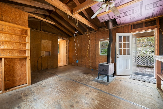 misc room with a wood stove, ceiling fan, and lofted ceiling