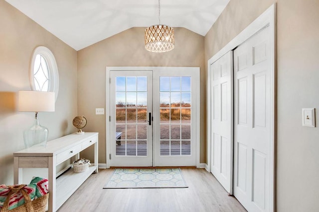 entryway with light hardwood / wood-style floors, lofted ceiling, and an inviting chandelier