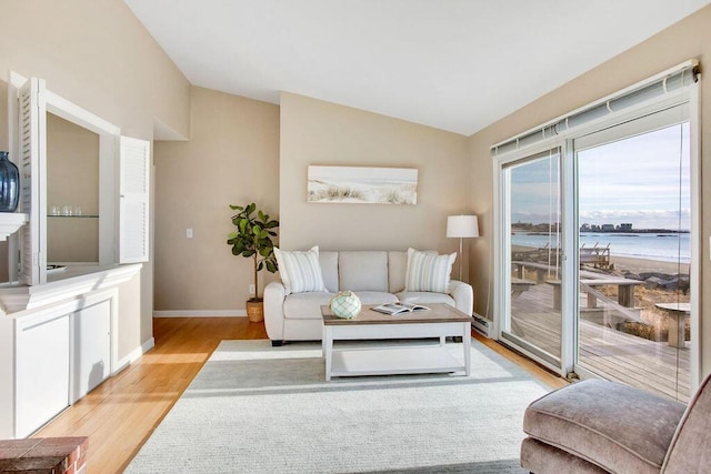 living room with light hardwood / wood-style flooring, a water view, and lofted ceiling