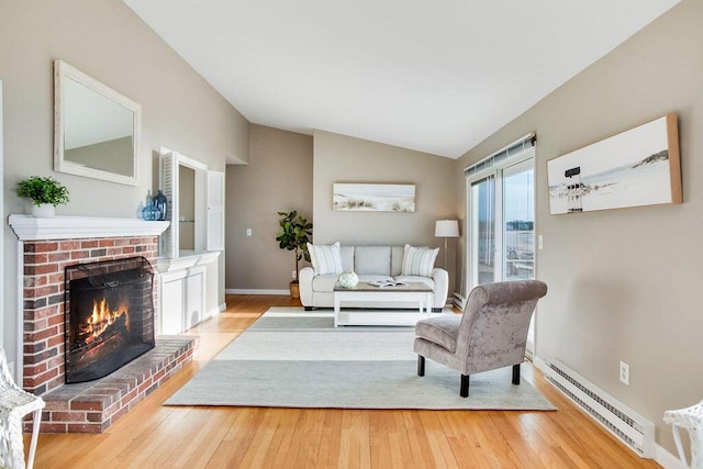 living room featuring baseboard heating, light hardwood / wood-style flooring, vaulted ceiling, and a brick fireplace